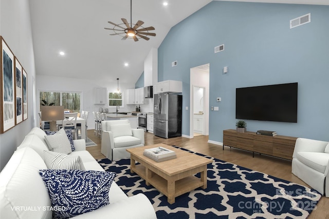 living room featuring visible vents, ceiling fan, baseboards, and wood finished floors