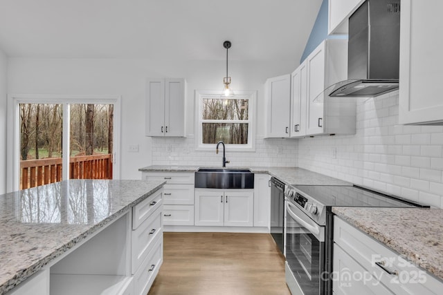 kitchen with white cabinets, stainless steel electric range oven, light stone counters, wall chimney range hood, and a sink