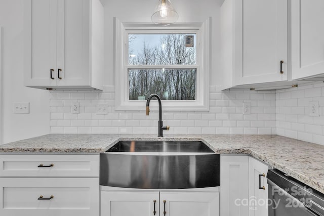 kitchen featuring light stone countertops, dishwasher, white cabinetry, and a sink