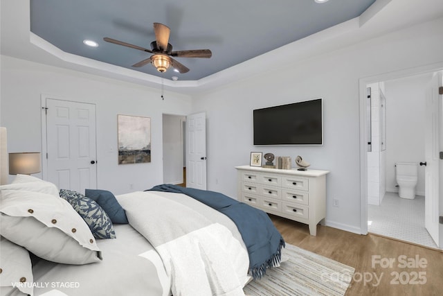 bedroom featuring ensuite bathroom, recessed lighting, a ceiling fan, light wood finished floors, and a raised ceiling