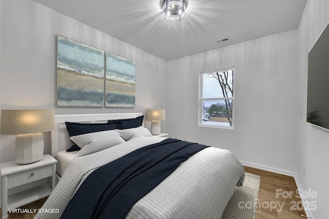 bedroom featuring wood finished floors, visible vents, and baseboards