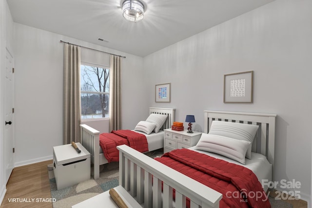 bedroom with visible vents, baseboards, and wood finished floors