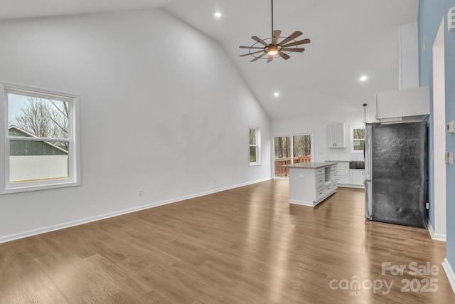 kitchen with a kitchen island, white cabinetry, open floor plan, freestanding refrigerator, and pendant lighting