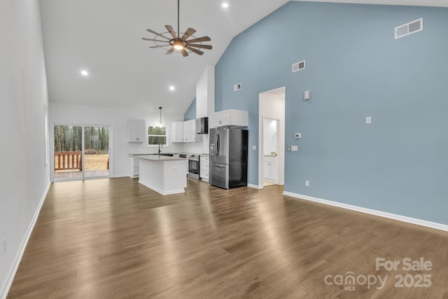 unfurnished living room with ceiling fan, dark wood-type flooring, visible vents, and baseboards