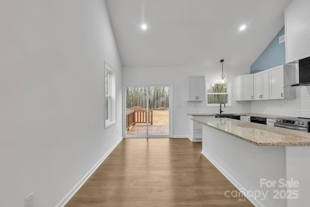 kitchen with a sink, a kitchen island, stainless steel range with electric cooktop, white cabinets, and decorative light fixtures