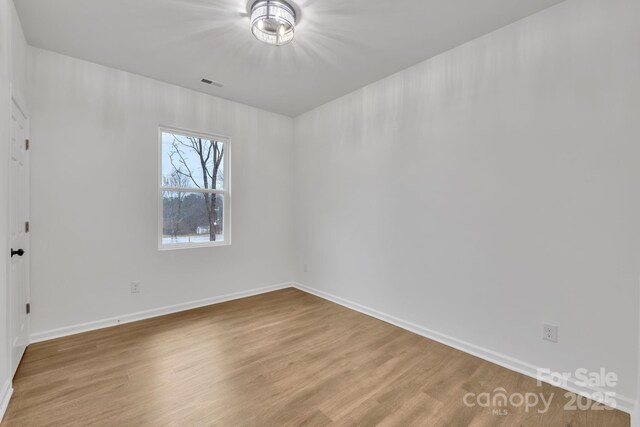 unfurnished room with visible vents, baseboards, and wood finished floors