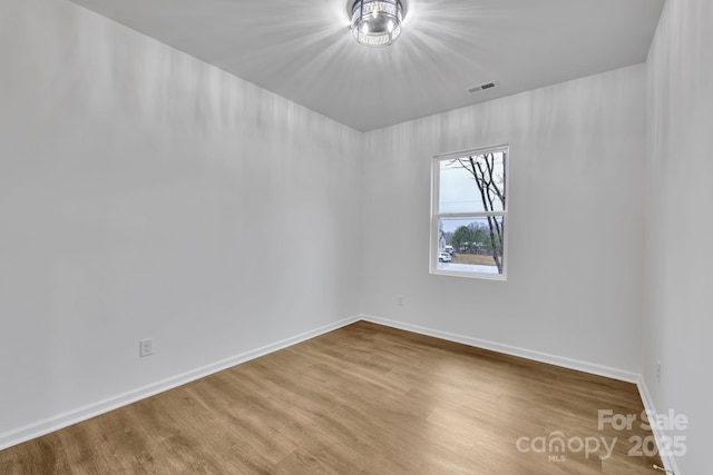 unfurnished room featuring visible vents, baseboards, and wood finished floors