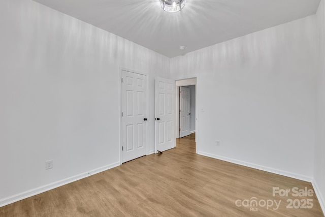 spare room featuring light wood-style flooring and baseboards