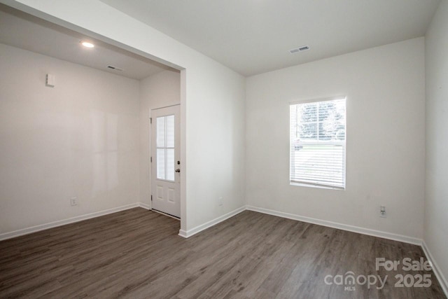 empty room featuring baseboards, visible vents, dark wood-type flooring, and recessed lighting