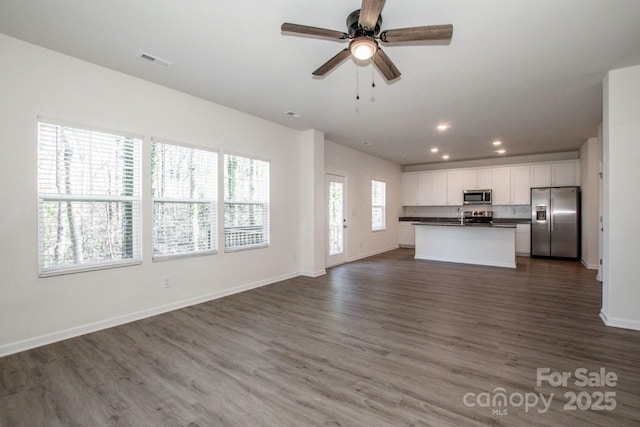 unfurnished living room with baseboards, visible vents, a ceiling fan, dark wood-style flooring, and recessed lighting