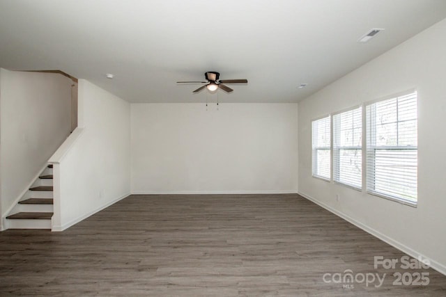 empty room with stairway, baseboards, visible vents, and dark wood-style flooring