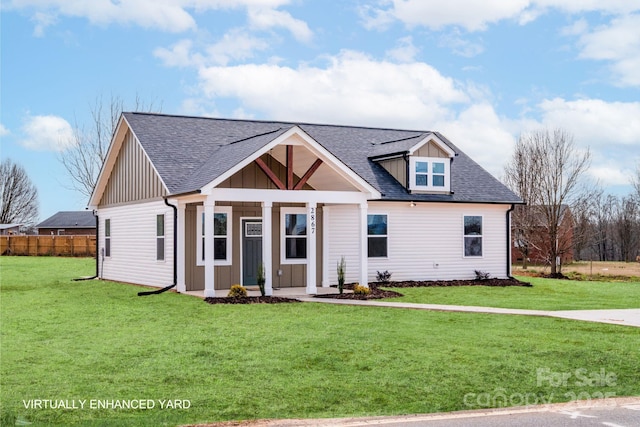 view of front of home with a shingled roof, a front lawn, board and batten siding, and fence