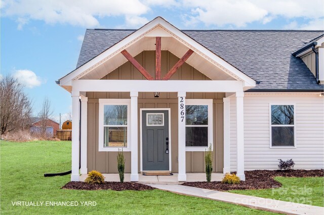 view of front of property featuring a shingled roof, board and batten siding, and a front lawn