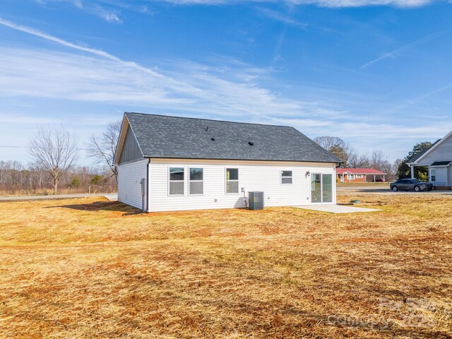 rear view of property with roof with shingles, a patio area, a yard, and central AC unit