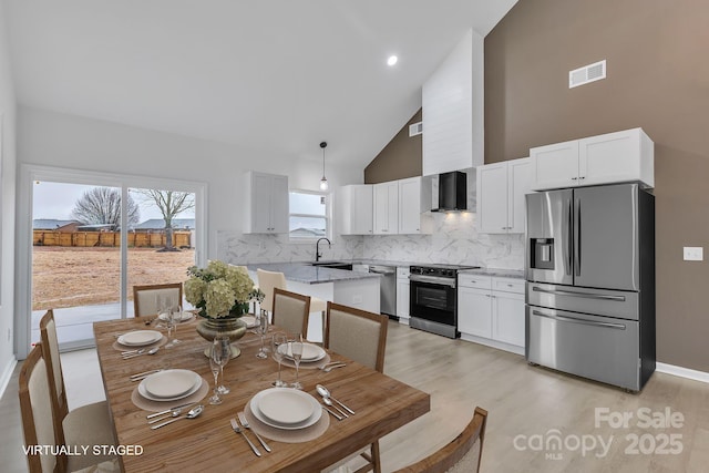 dining area featuring high vaulted ceiling, baseboards, visible vents, and light wood-style floors