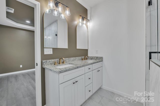 bathroom with double vanity, baseboards, visible vents, and a sink