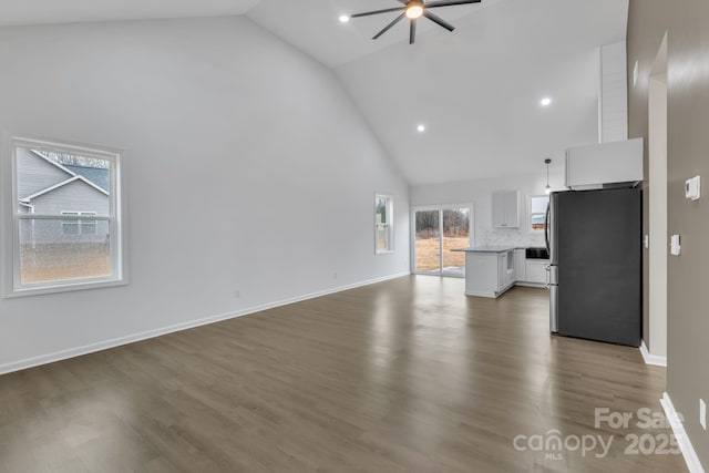 unfurnished living room with baseboards, ceiling fan, dark wood-style flooring, high vaulted ceiling, and recessed lighting