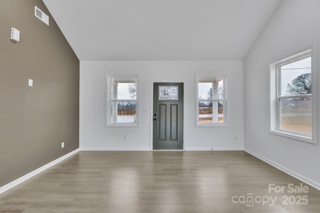 foyer with lofted ceiling, light wood finished floors, visible vents, and baseboards