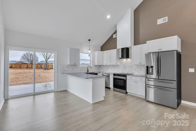 kitchen featuring pendant lighting, appliances with stainless steel finishes, white cabinetry, light stone countertops, and a peninsula