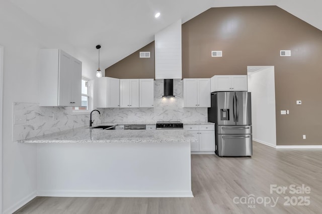 kitchen featuring wall chimney exhaust hood, white cabinets, hanging light fixtures, and stainless steel fridge with ice dispenser