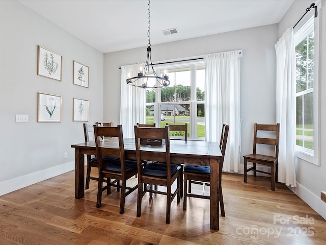 dining space with hardwood / wood-style floors and a notable chandelier