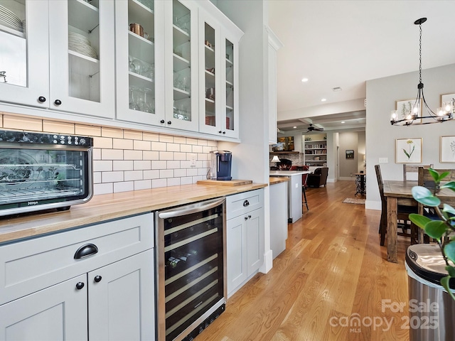 bar with wine cooler, backsplash, pendant lighting, and white cabinets