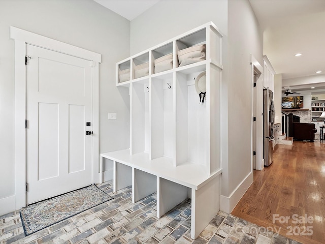 mudroom featuring ceiling fan and a fireplace