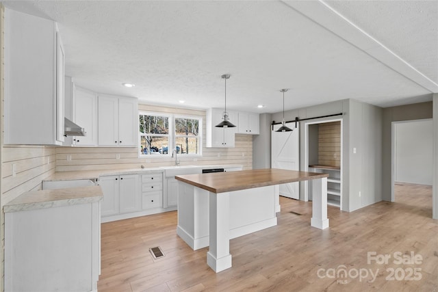 kitchen with a kitchen island, pendant lighting, sink, white cabinets, and a barn door