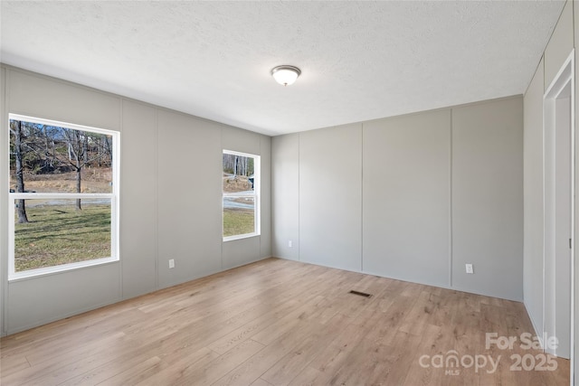 unfurnished room featuring a textured ceiling and light hardwood / wood-style flooring