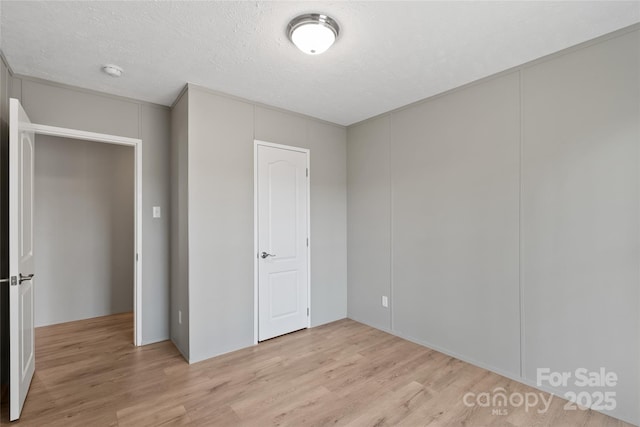 unfurnished bedroom with a textured ceiling and light hardwood / wood-style flooring