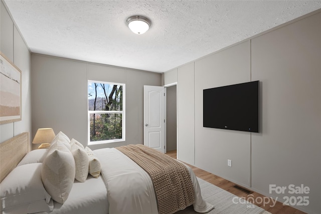 bedroom with hardwood / wood-style flooring and a textured ceiling