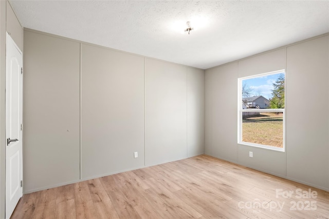 unfurnished room with light hardwood / wood-style floors and a textured ceiling