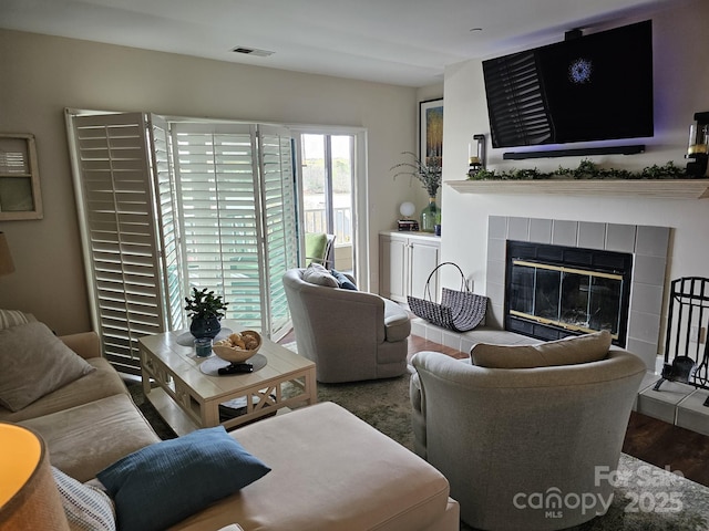 living room with hardwood / wood-style flooring and a tiled fireplace