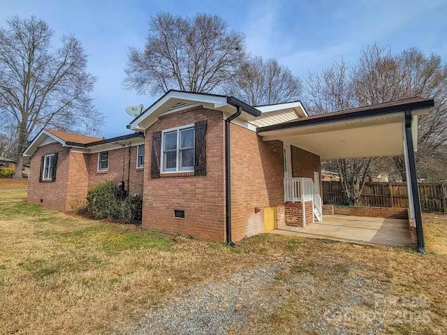 view of side of home featuring a lawn, crawl space, fence, a patio area, and brick siding