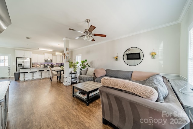 living area featuring crown molding, visible vents, ceiling fan, and wood finished floors