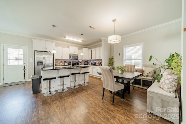 dining room with crown molding, visible vents, and dark wood finished floors