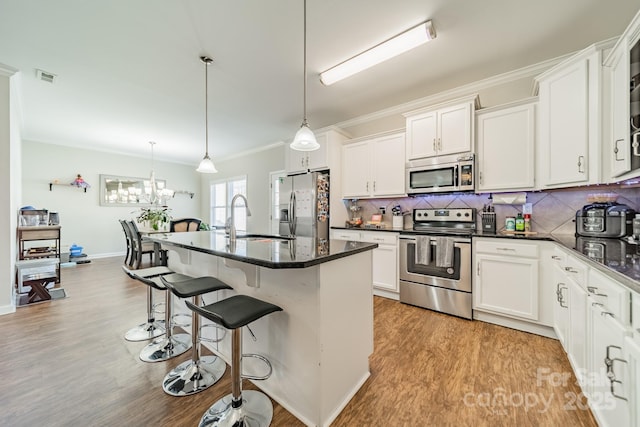 kitchen with stainless steel appliances, a sink, white cabinetry, and pendant lighting