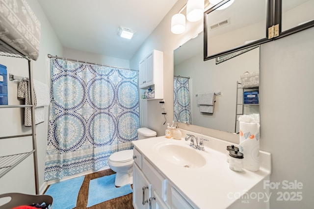 full bathroom featuring visible vents, toilet, wood finished floors, curtained shower, and vanity