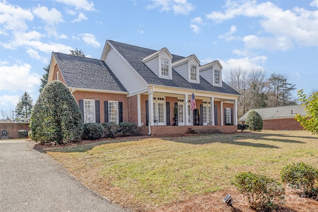 cape cod house featuring a porch and a front lawn