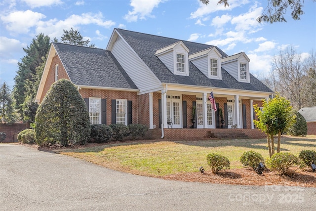 cape cod home with covered porch and a front lawn