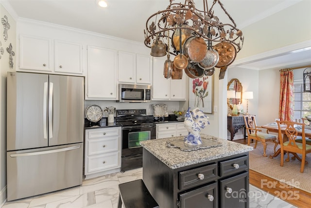 kitchen featuring an inviting chandelier, white cabinetry, a center island, ornamental molding, and stainless steel appliances
