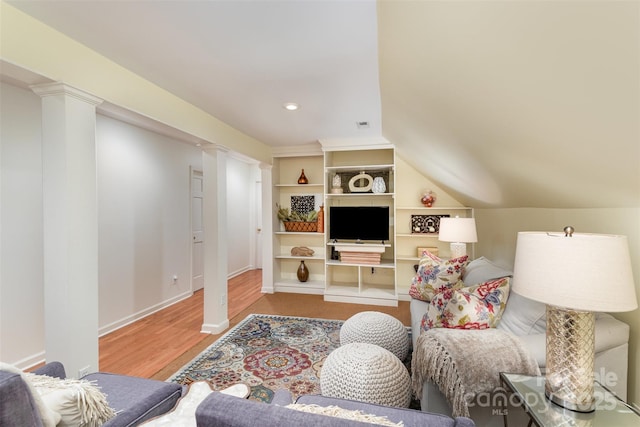living room with ornate columns, lofted ceiling, and hardwood / wood-style floors