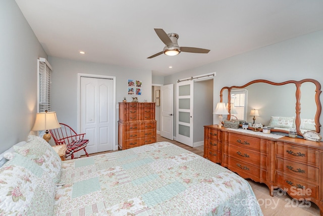 bedroom featuring recessed lighting, ceiling fan, a closet, and a barn door