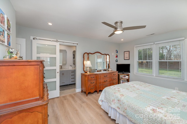 bedroom with visible vents, light wood-style flooring, ceiling fan, recessed lighting, and a barn door