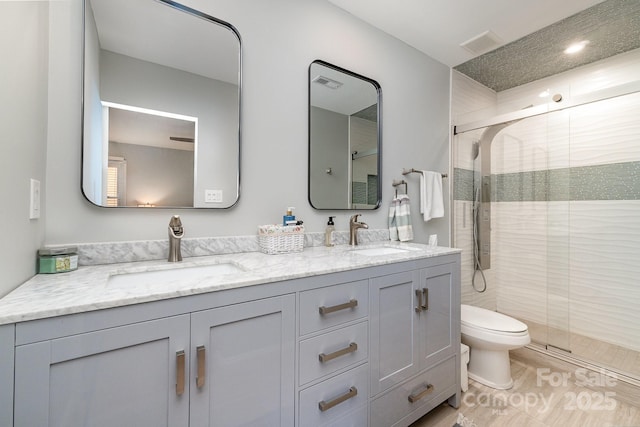 bathroom with a stall shower, visible vents, double vanity, and a sink