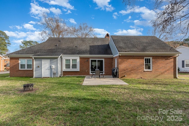 rear view of house featuring a shingled roof, brick siding, a patio, and a lawn