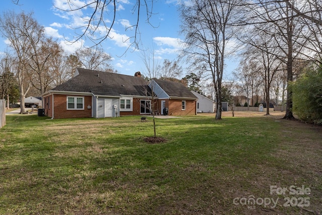 back of house with brick siding, a yard, and a chimney