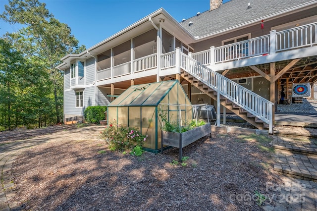 back of house featuring an outbuilding and a sunroom