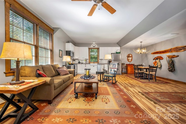 living room featuring ceiling fan with notable chandelier and light wood-type flooring