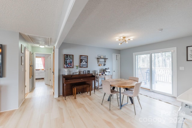 dining area with attic access, light wood-type flooring, and a textured ceiling